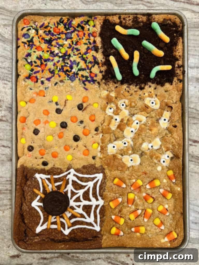 An overhead view of the partially decorated Halloween cookie bars, showcasing the distinct sections before final garnishes, set on a gray and white marble counter.