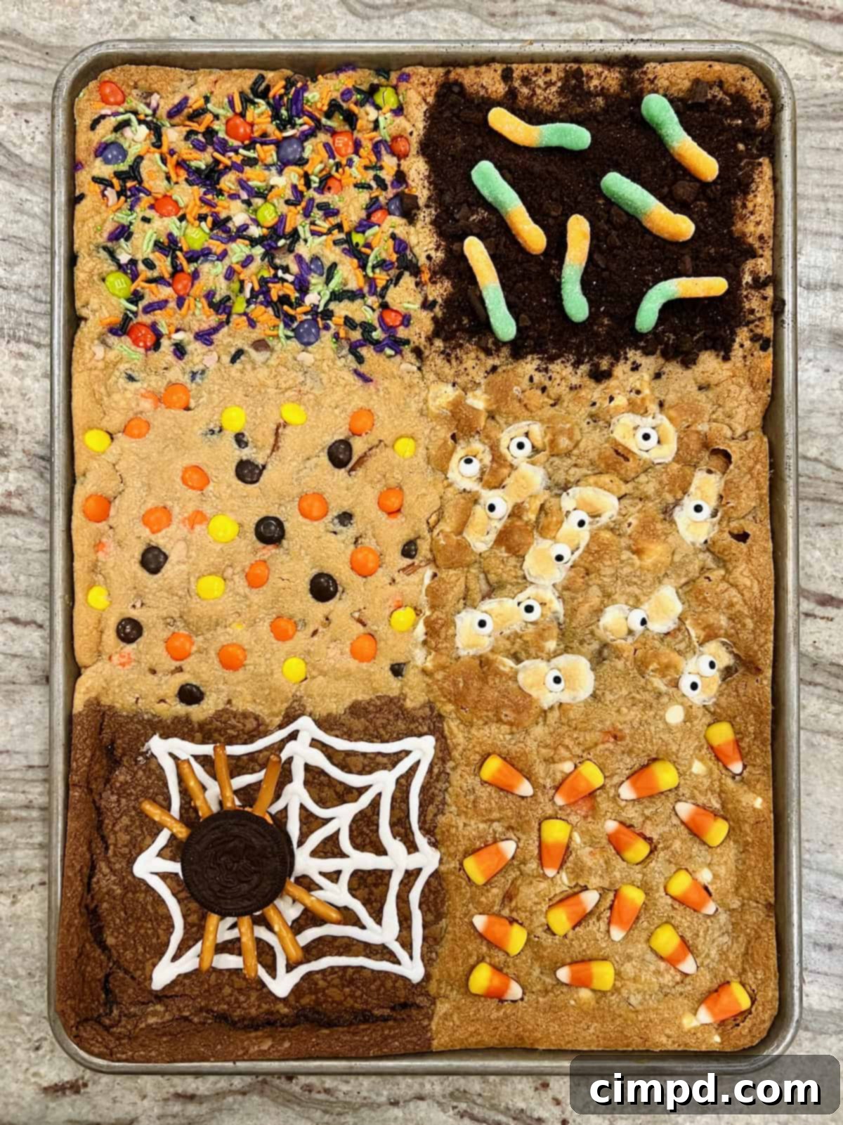 A full sheet pan of Halloween cookie bars displayed on a gray and white marble counter, ready to be cut and served.