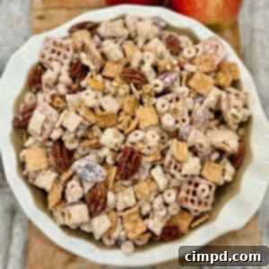 A white scalloped bowl brimming with Apple Pie Snack Mix, expertly photographed in a square format for recipe cards, highlighting its delicious appeal.