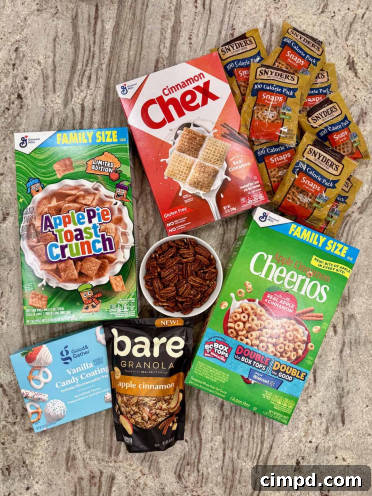 A vibrant flat lay photo displaying all the fresh, high-quality ingredients required to make the Apple Pie Snack Mix, neatly arranged on a modern gray and white counter, ready for assembly.