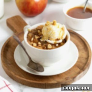 Spiced Apple Mug Delight 13 A beautiful apple cake nestled in a white mug on a round wooden cutting board, perfectly representing the single-serving indulgence.