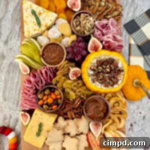 Autumn's Canvas: A Community Art Project 7 A rectangular wooden food board filled with autumnal snacks like cheese, salami, sliced pear and a pumpkin dip.