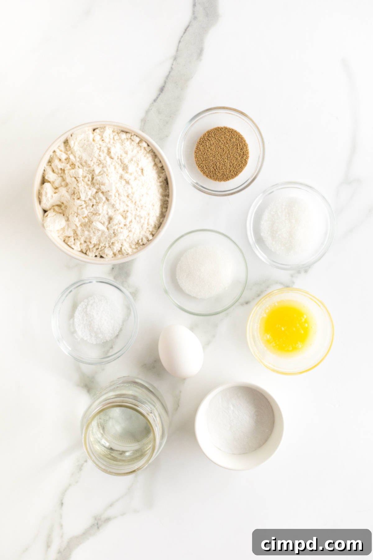 All the necessary ingredients neatly arranged in small glass dishes on a pristine white counter, ready to be transformed into delicious pretzels.