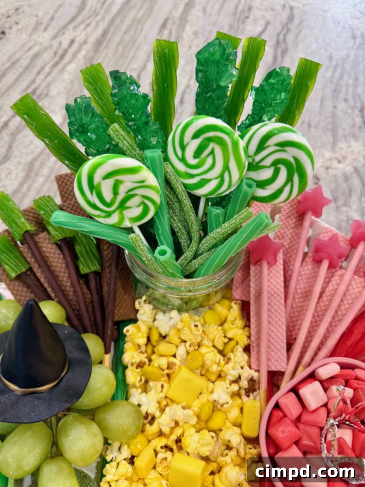 Green lollipops, rock candy, and sour candy sticks arranged to form the 'Emerald City' in a clear mason jar.