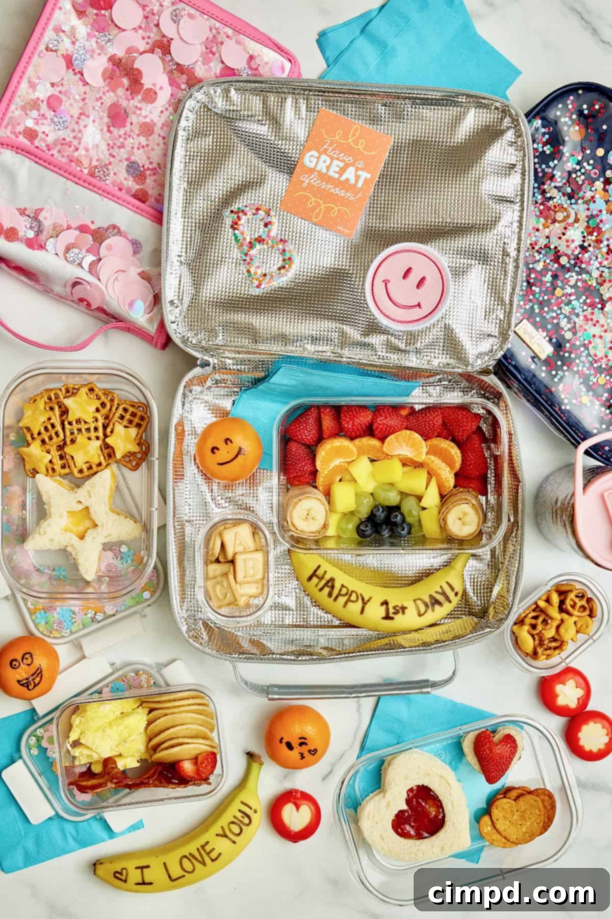 Deliciously Healthy School Lunches Kids Will Love 3 A collection of appealing school lunchbox examples: one with a rainbow fruit arrangement and a 'Happy First Day of School' banana, another with mini pancakes, scrambled eggs, and sliced strawberries, and a third featuring a star-shaped cheese sandwich with star cheese cut-outs on pretzels.