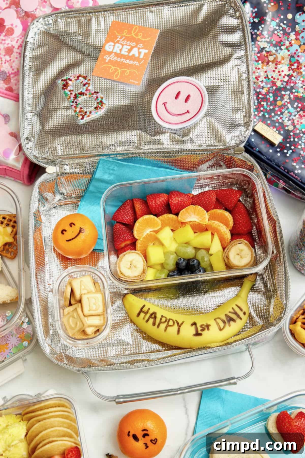 Deliciously Healthy School Lunches Kids Will Love 5 A school lunchbox meticulously arranged with a rainbow of colorful fruits, complemented by a banana inscribed with 'Happy First Day of School'.