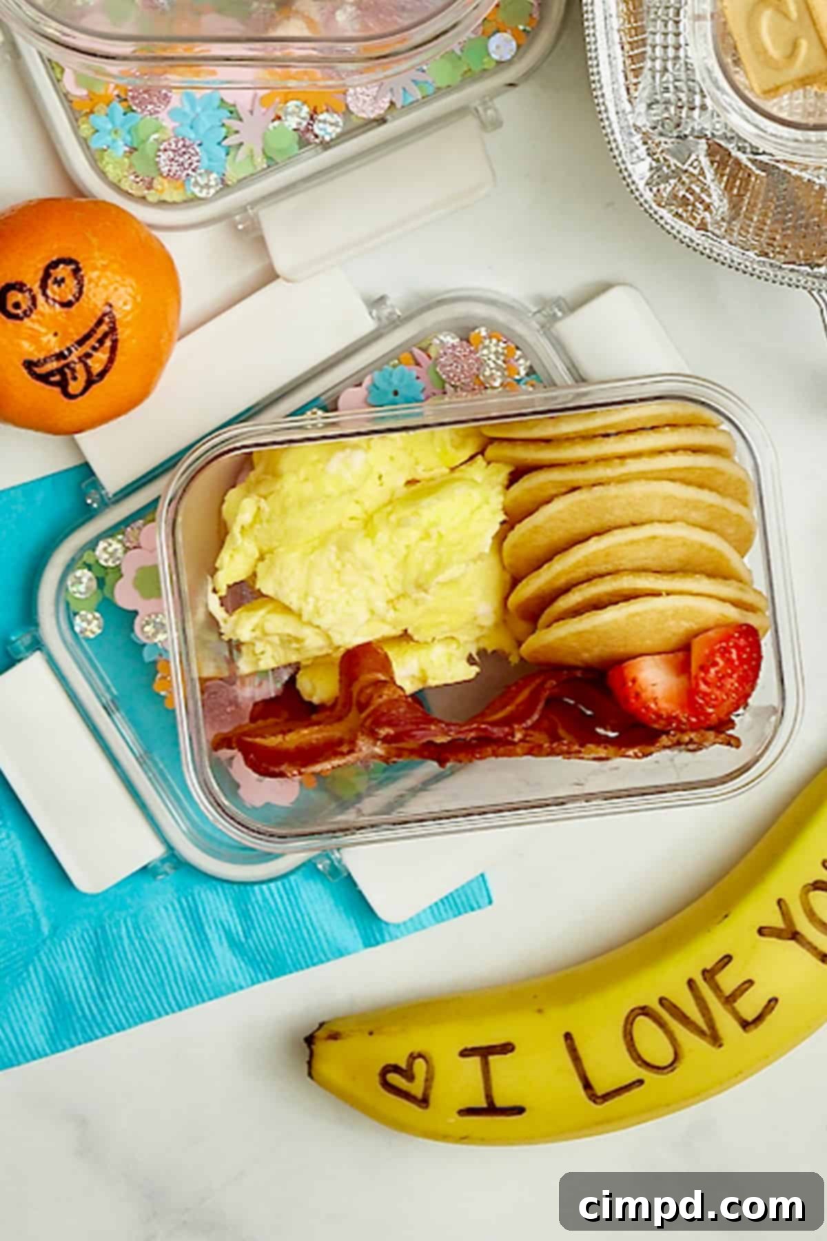 Deliciously Healthy School Lunches Kids Will Love 7 A delightful brunch-themed lunchbox featuring fluffy mini pancakes, perfectly scrambled eggs, and fresh sliced strawberries, offering a unique midday meal.