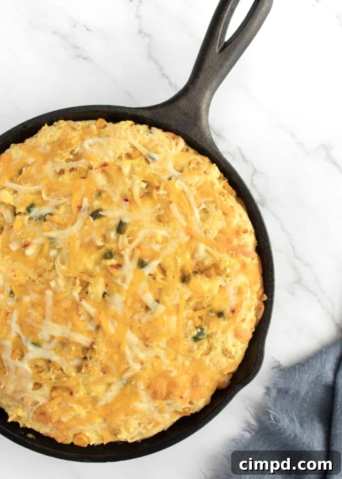 Cheesy Corn Cornbread in a cast iron skillet on a white marble counter, ready to be served.