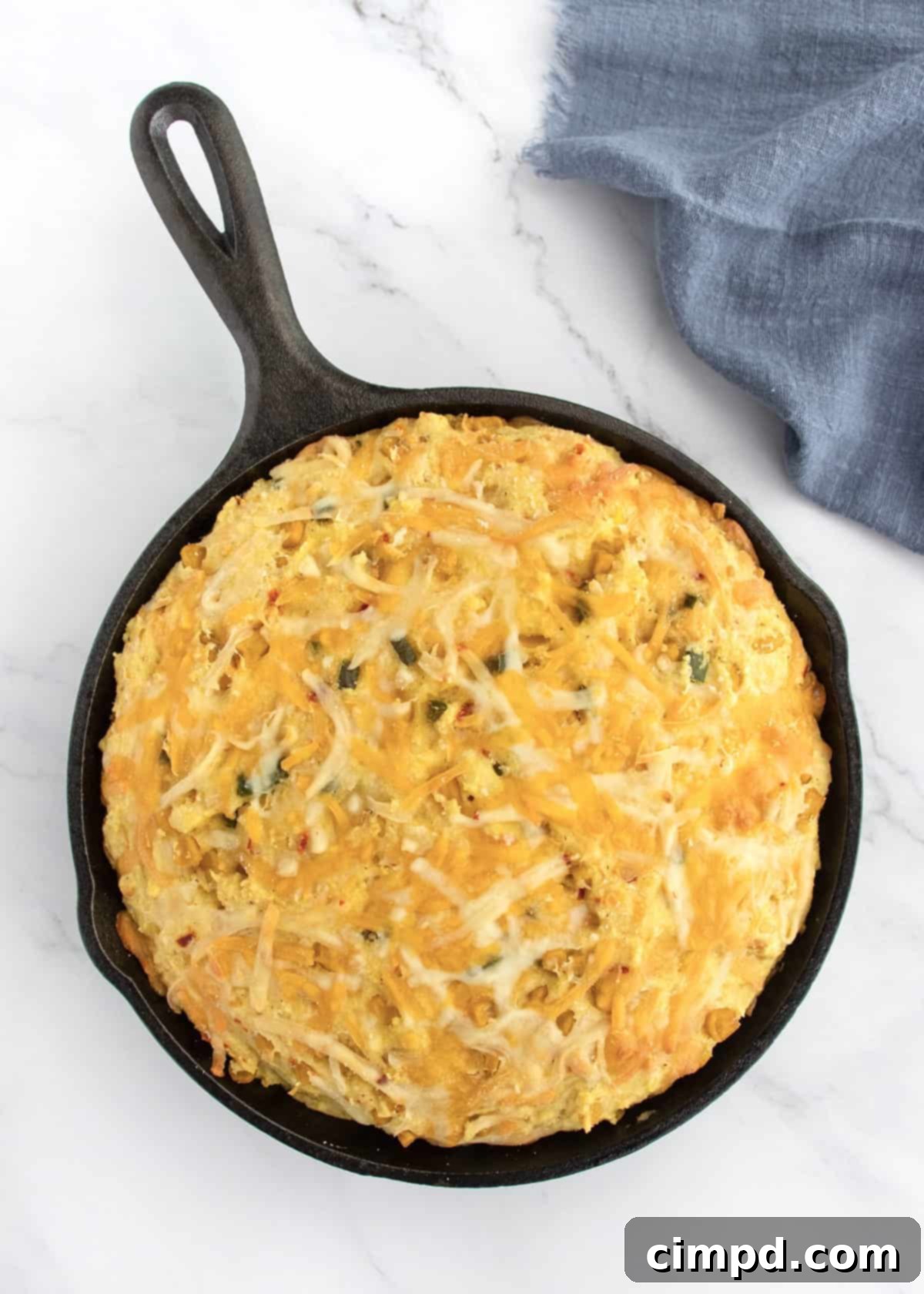A freshly baked Cheesy Corn Cornbread in a skillet on a cooling rack.