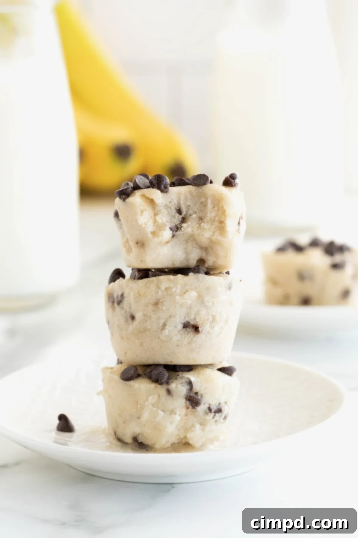 Three banana chocolate chip frozen bites stacked on a white plate, showcasing their inviting texture.
