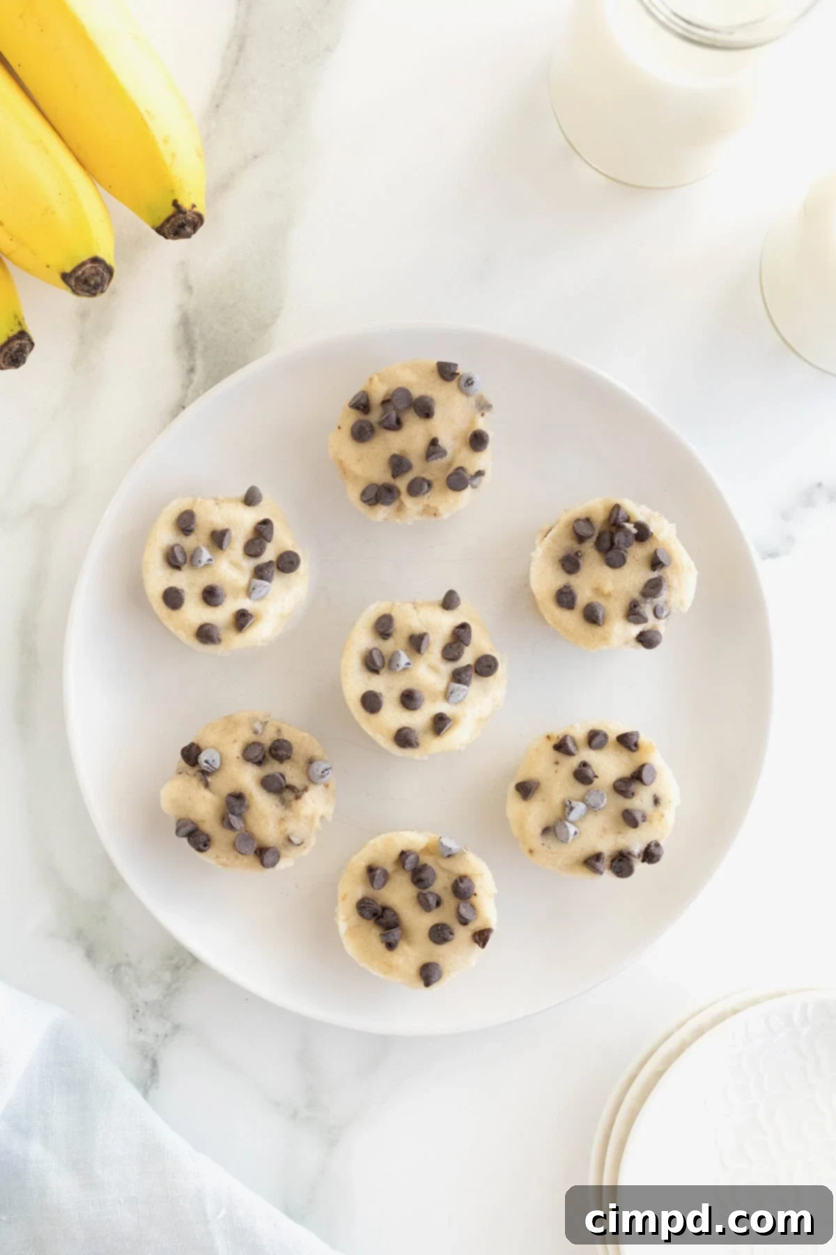 A large white plate artfully arranged with seven banana ice cream bites, forming an inviting circle.
