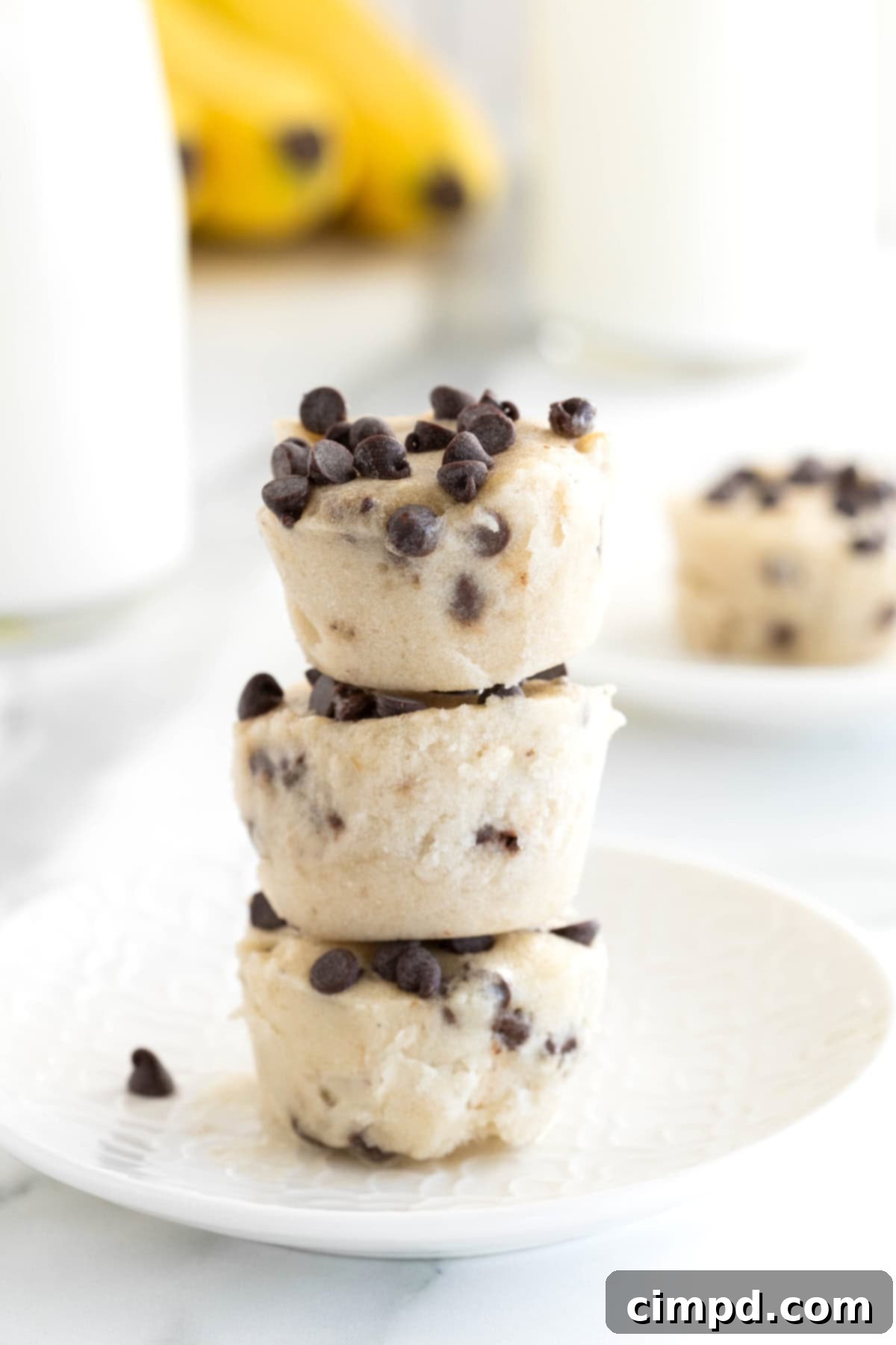 Three perfectly stacked banana chocolate chip frozen bites on a clean white plate, ready to be enjoyed.