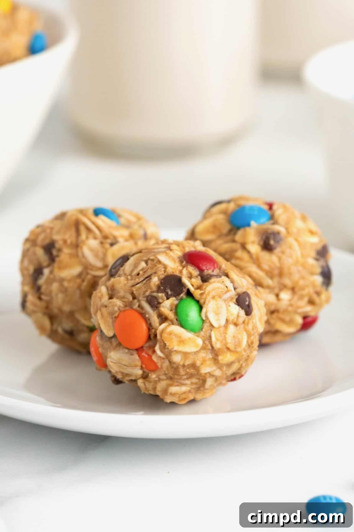 No-Bake Monster Cookie Bites 4 A trio of vibrant monster cookie balls artfully arranged on a small white plate, ready to be enjoyed.