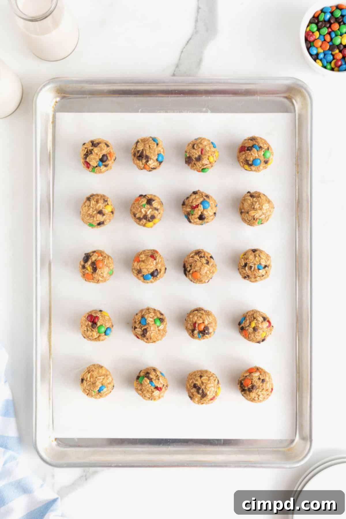No-Bake Monster Cookie Bites 10 A baking sheet filled with 20 freshly rolled no-bake cookie balls, neatly arranged on parchment paper, awaiting their chilling time.