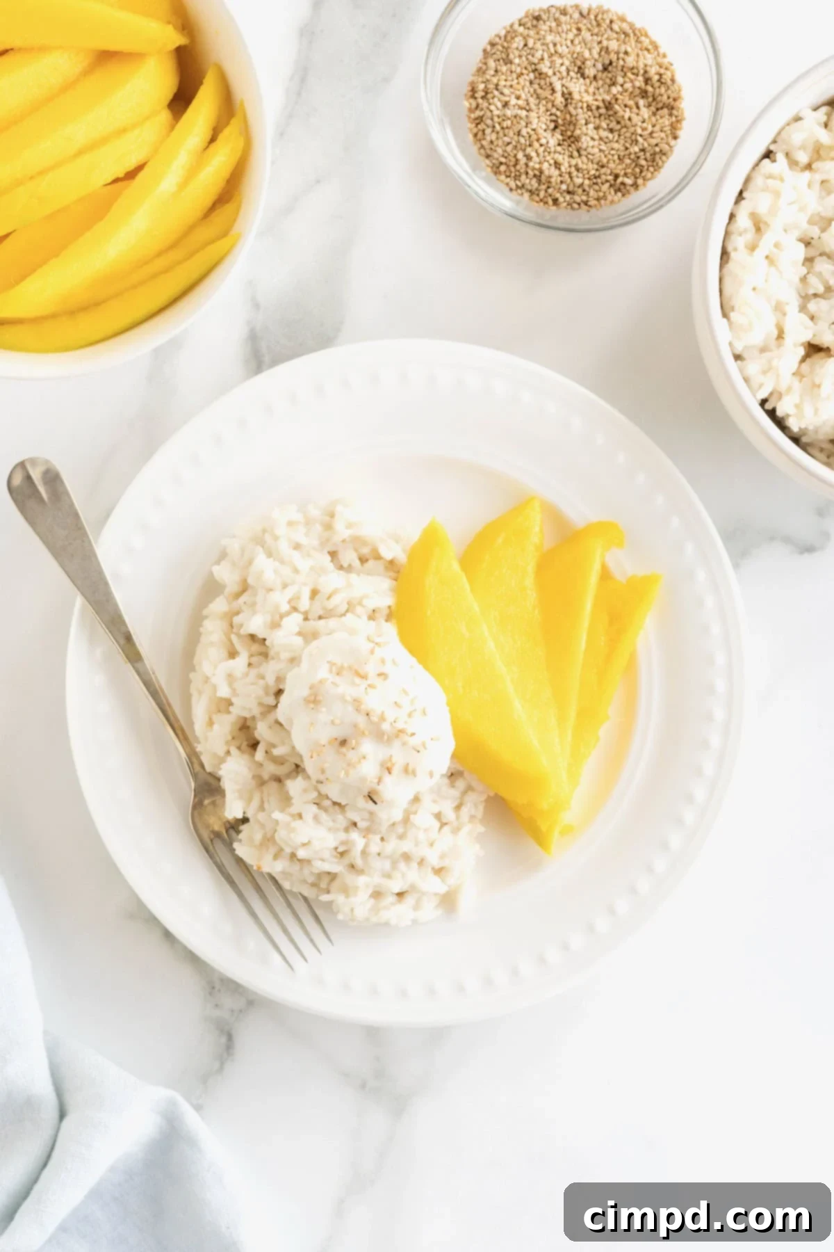A small white plate with slices of mango and sticky rice, ready to be enjoyed.