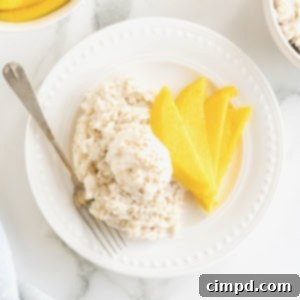A small white plate with slices of mango and sticky rice.