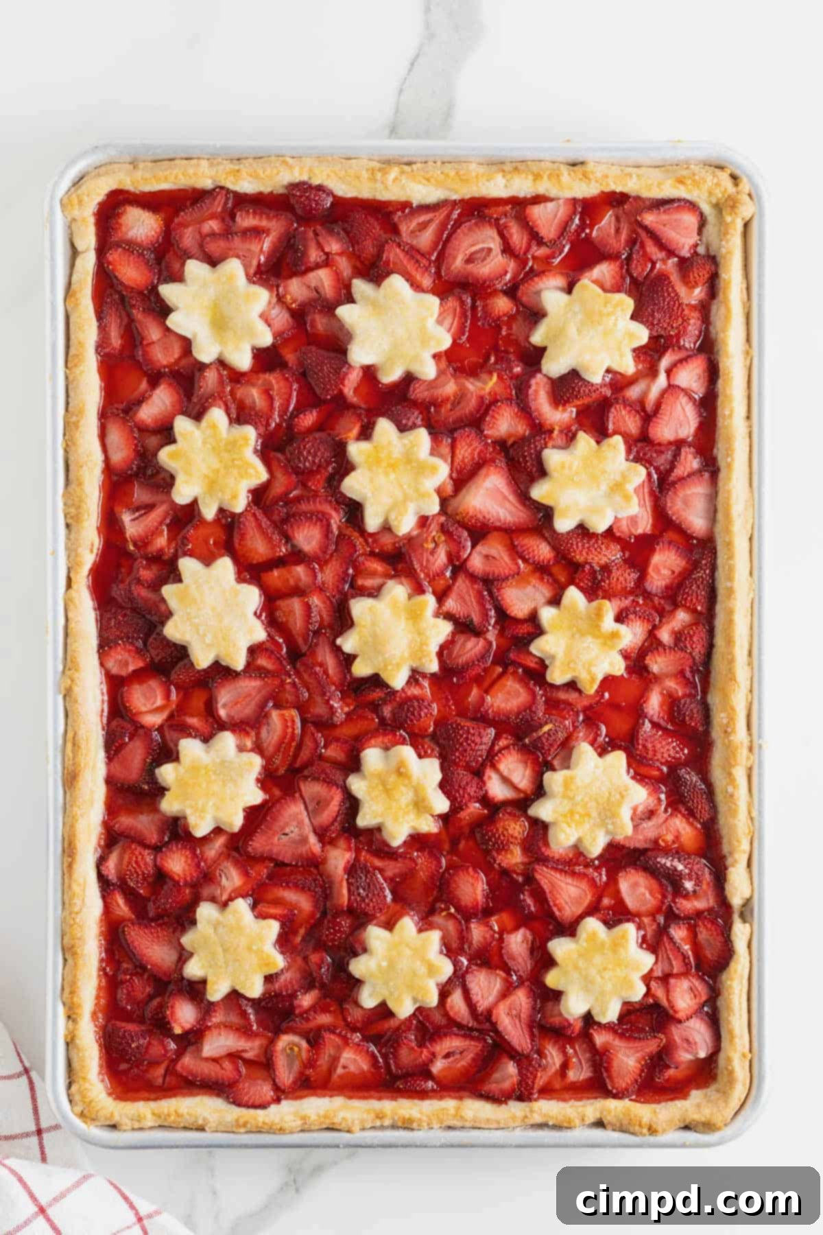 Summer Strawberry Slab Pie 9 A freshly baked Strawberry Slab Pie, golden and bubbling, resting on a white marble counter, ready to cool and be enjoyed.