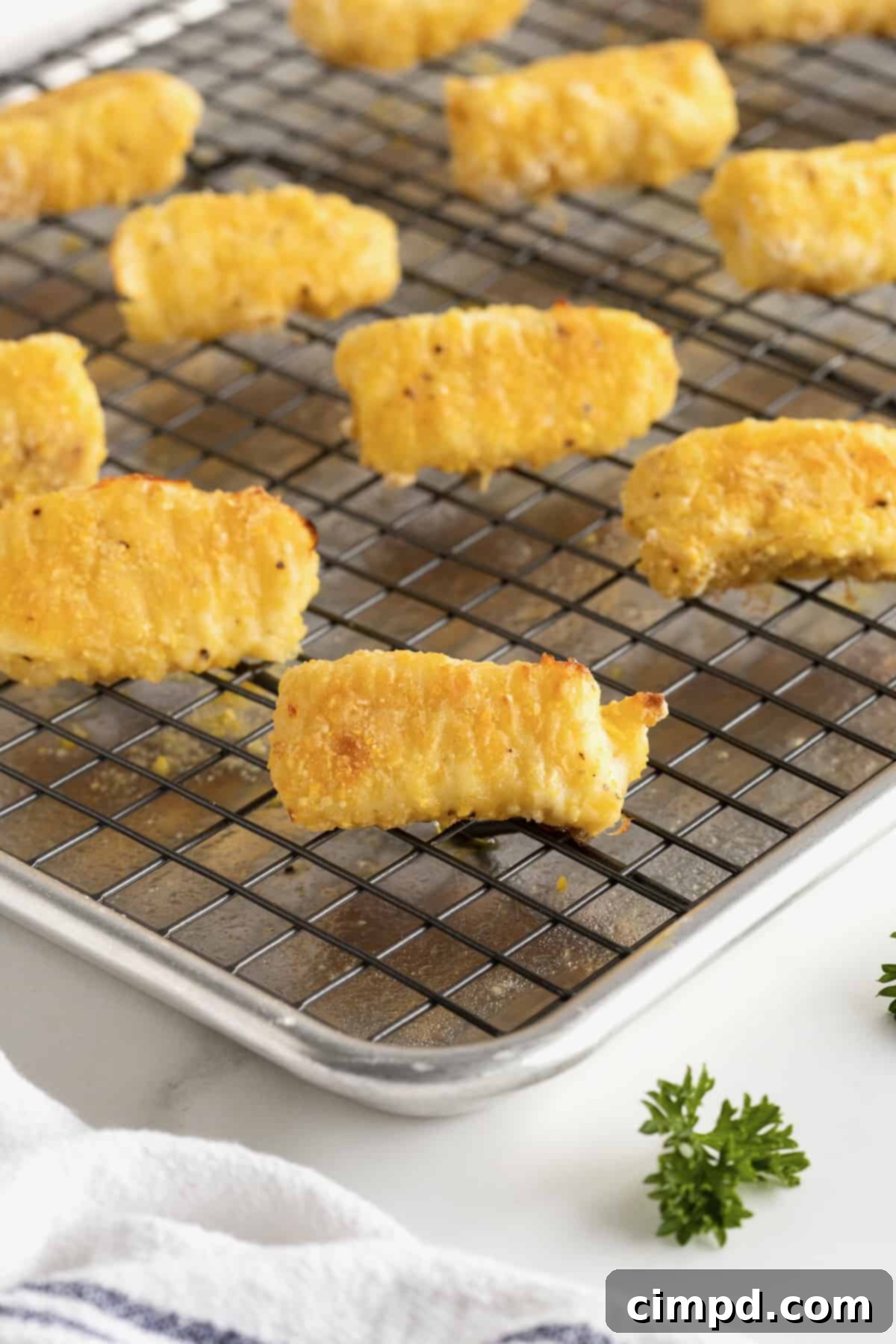 Crispy Baked Fish Fingers 12 A wire cooking rack on a baking sheet with six perfectly golden baked fish sticks on top, ready for serving or storage.