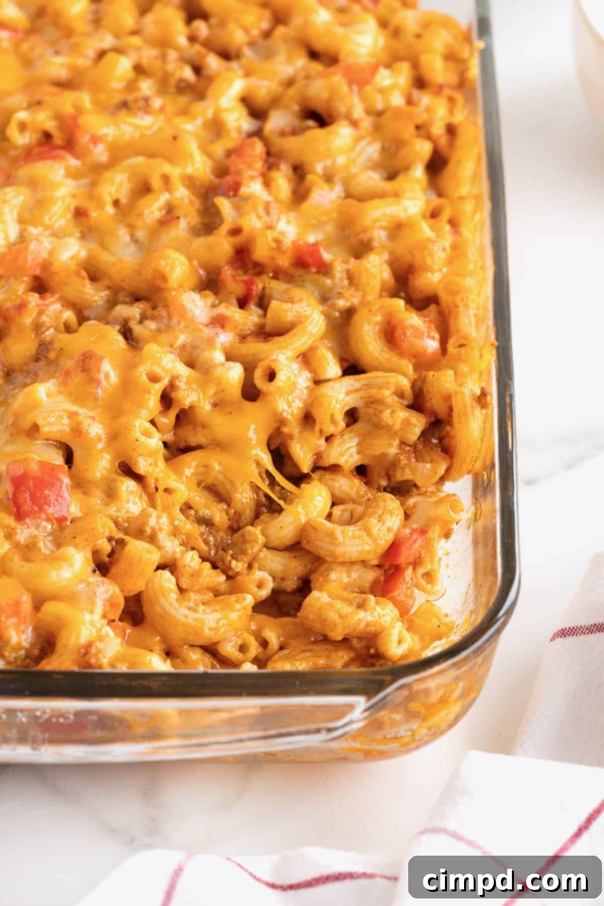 Fiesta Mac and Cheese 6 A glass casserole dish of Mexi Mac and Cheese, featuring elbow macaroni, visible chunks of red tomato, and a generous layer of melted yellow and white cheese.
