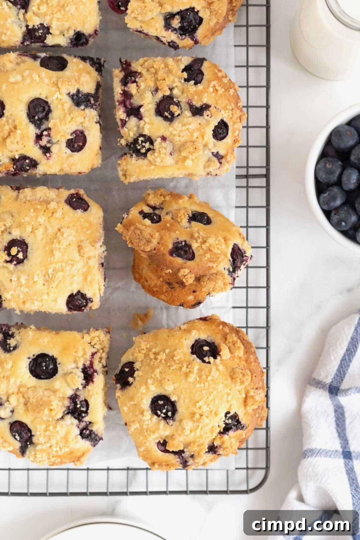 Blueberry streusel muffins cooling on a parchment-lined wire rack, ready for storage or immediate enjoyment.