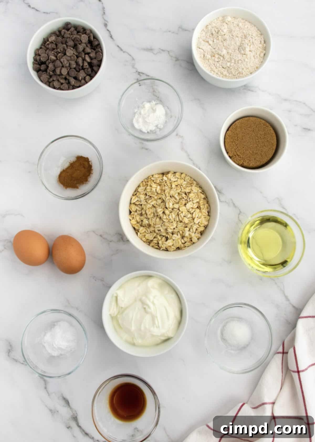 Greek Yogurt Chocolate Chip Oat Muffins 4 Ingredients for Oatmeal Chocolate Chip Greek Yogurt Muffins laid out on a kitchen counter, showcasing fresh and dry components.