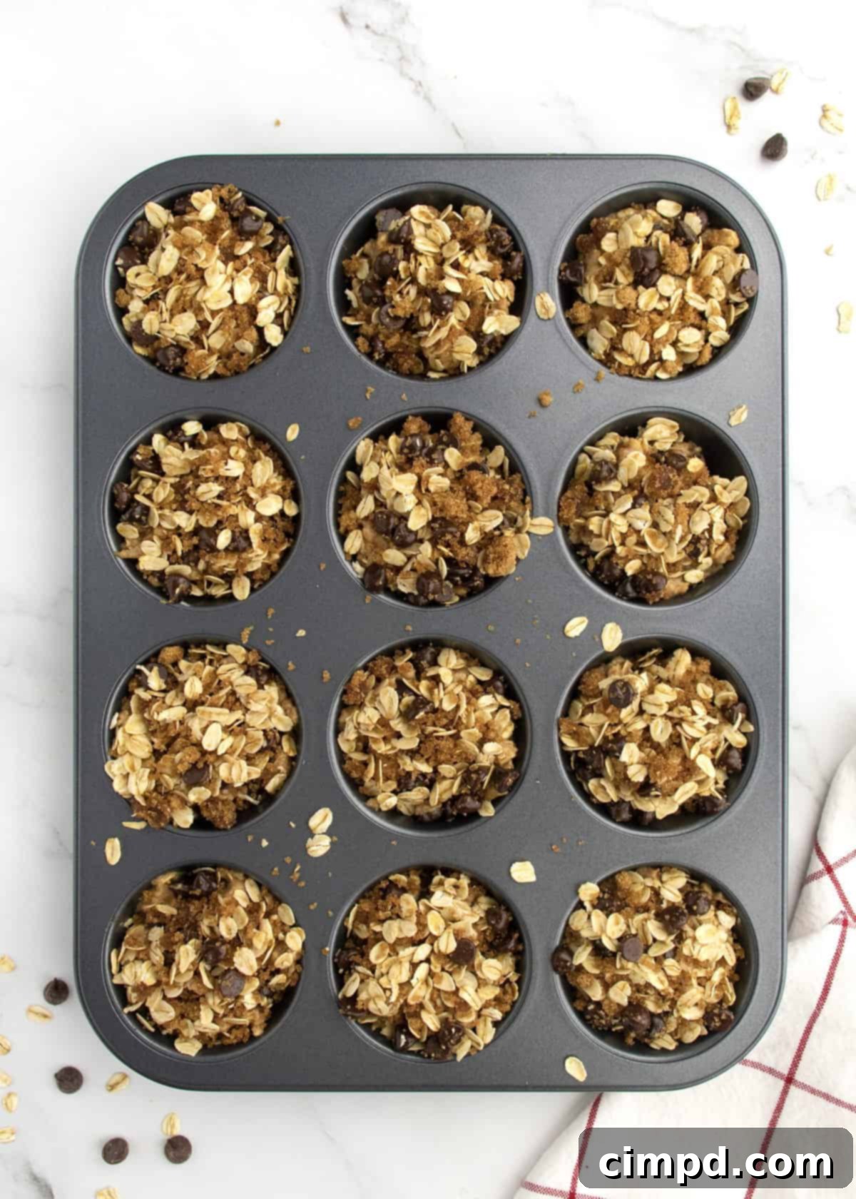 Greek Yogurt Chocolate Chip Oat Muffins 6 Close-up of muffin batter in a tin, topped with streusel and chocolate chips, ready for baking.