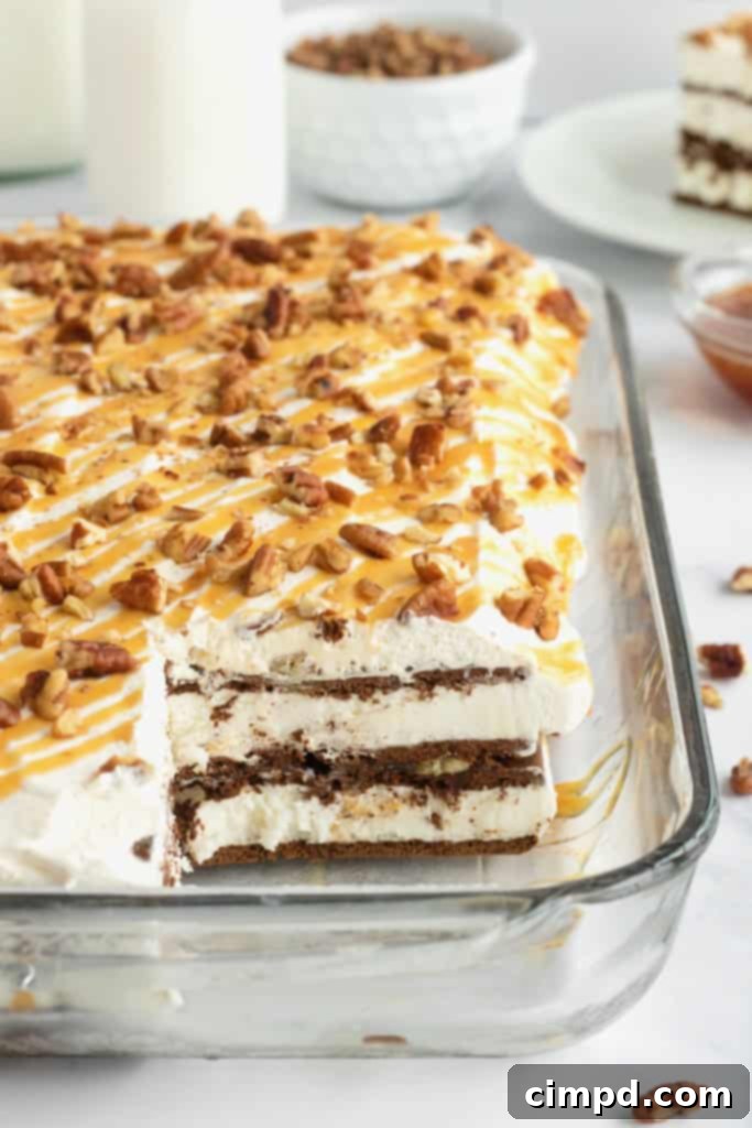 Ice cream sandwich cake topped with whipped cream, chopped pecans and a caramel drizzle in a pyrex dish.