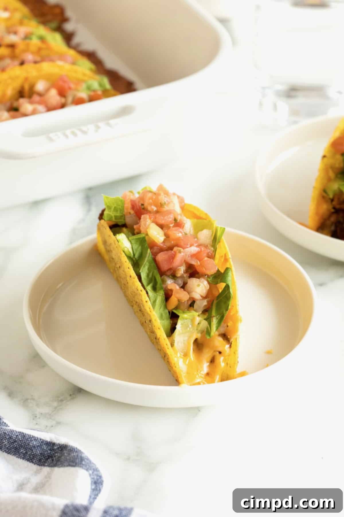 A single baked turkey and black bean taco, topped with fresh chopped tomatoes and vibrant shredded lettuce, served on a white round plate with a subtle rim.