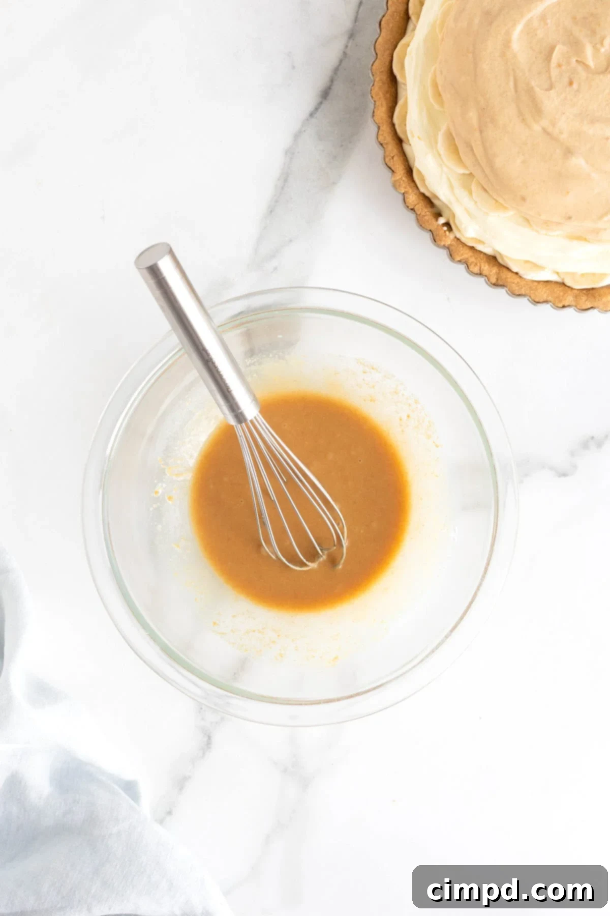 Peanut butter sauce in a small glass bowl with a metal whisk.