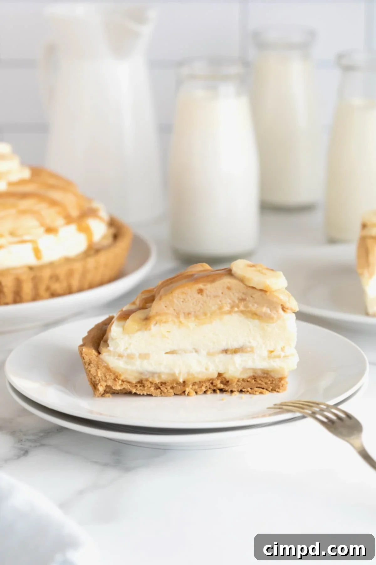 A slice of peanut butter banana cream pie on a small white dessert plate with a fork.