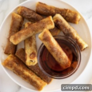 Cinnamon sugar covered French toast roll ups surrounding a glass bowl of warmed maple syrup.