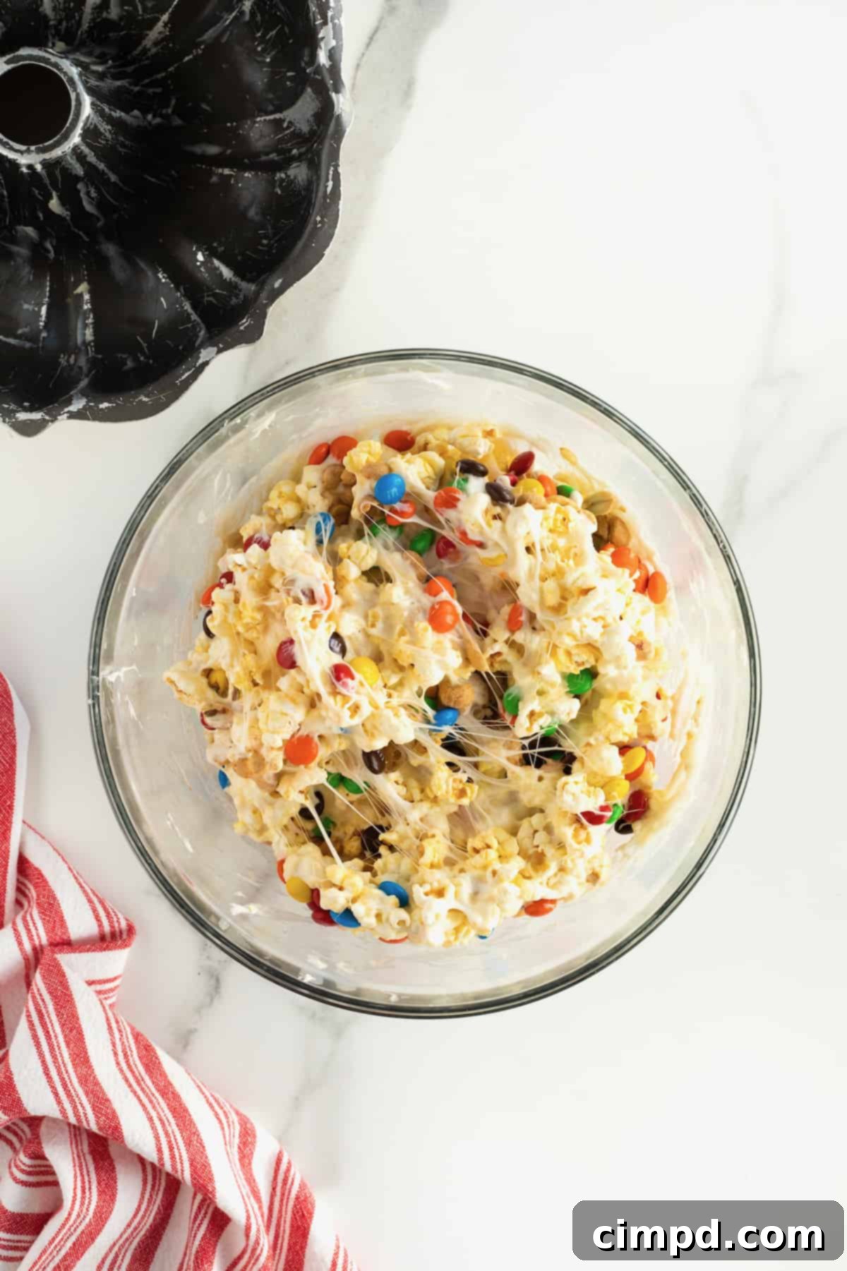 A large glass bowl filled with a delightful mix of peanut popcorn and M&M's, ready for the next step.