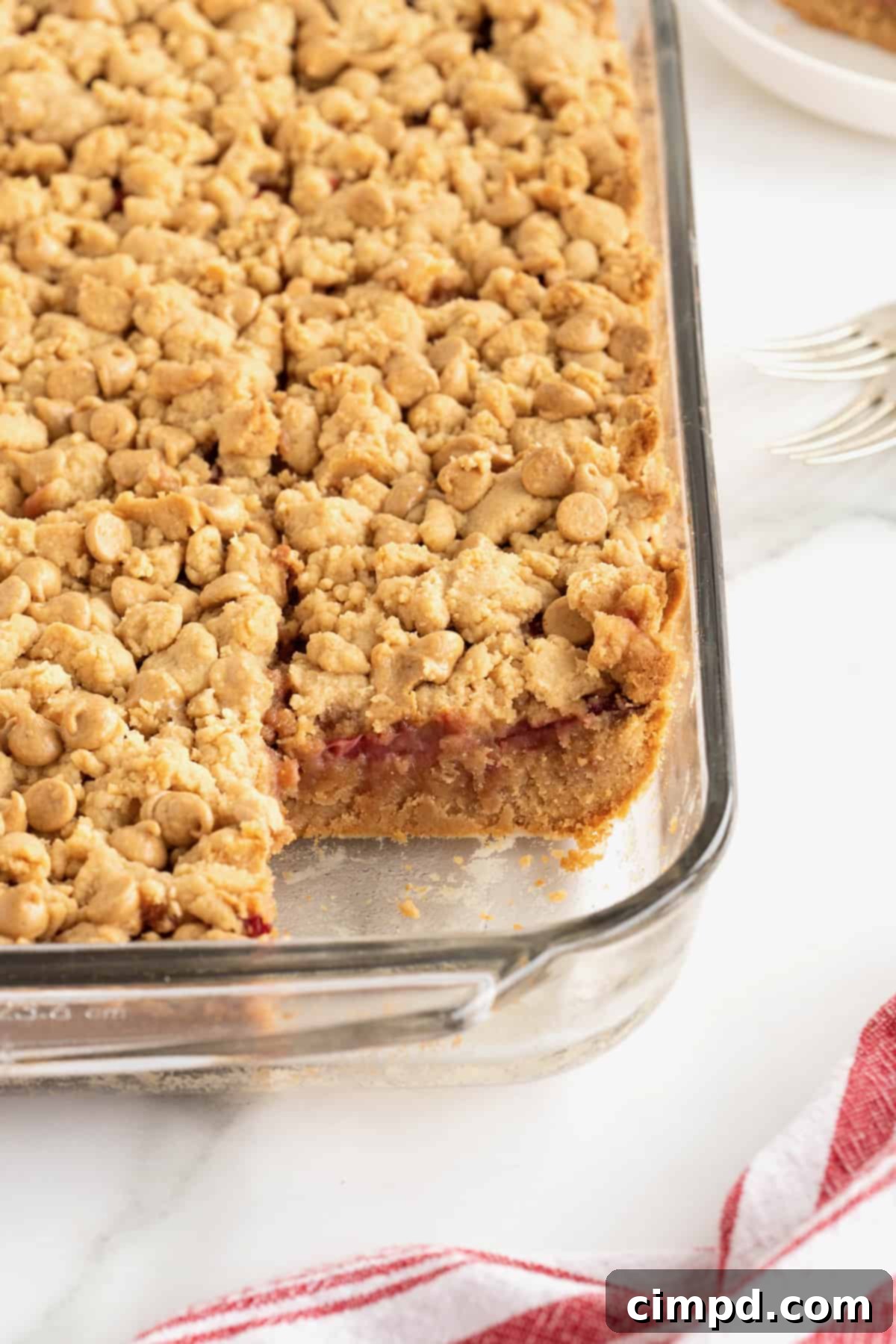 Strawberry Peanut Butter Swirl Bars 11 A 9x13 glass dish filled with strawberry peanut butter bars, with one bar removed from the bottom right corner, resting on a white marble counter.