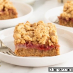 Strawberry Peanut Butter Swirl Bars 13 A single strawberry peanut butter bar on a white rimmed plate with a fork.