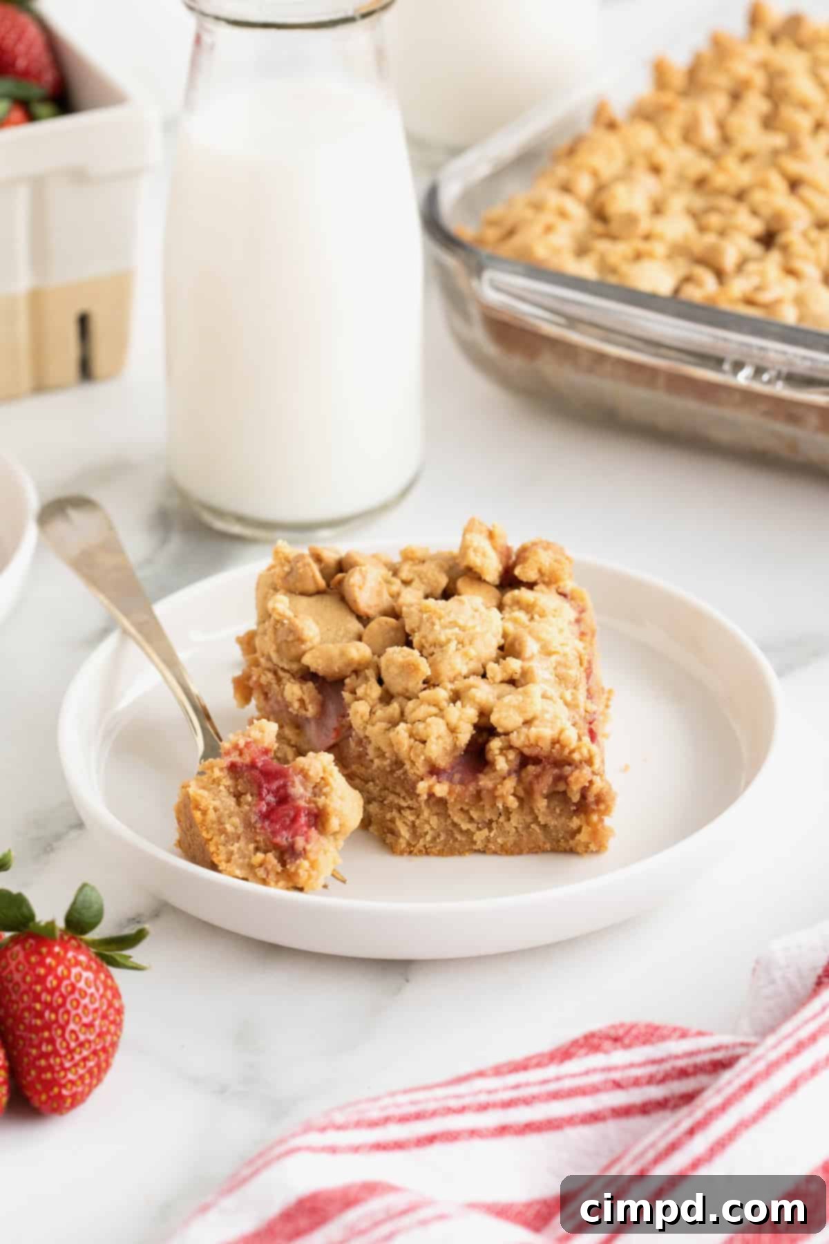 Strawberry Peanut Butter Swirl Bars 5 A close-up of strawberry peanut butter bars on white plates, with a glass jar of milk in the soft-focus background, highlighting a perfect pairing.