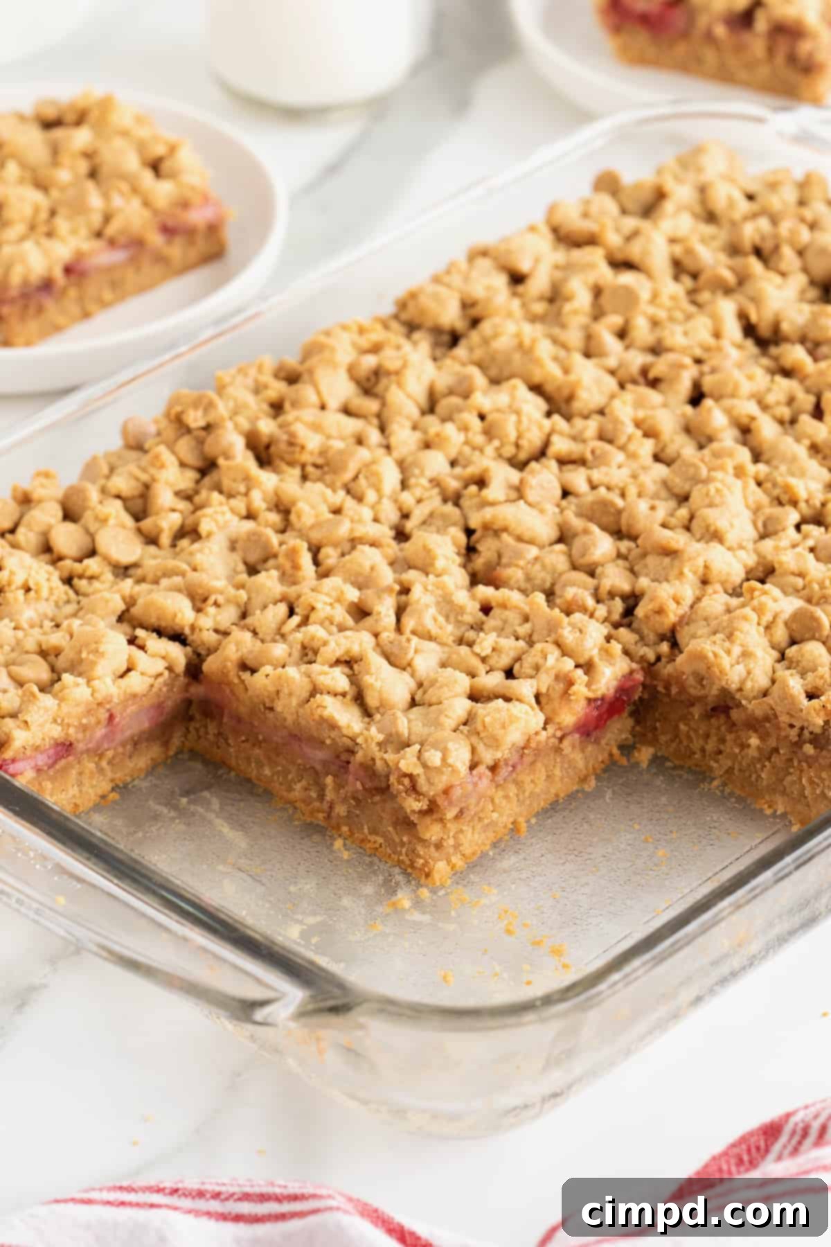 Strawberry Peanut Butter Swirl Bars 6 A 9x13 glass baking dish filled with freshly baked strawberry peanut butter bars, resting on a clean white marble counter.