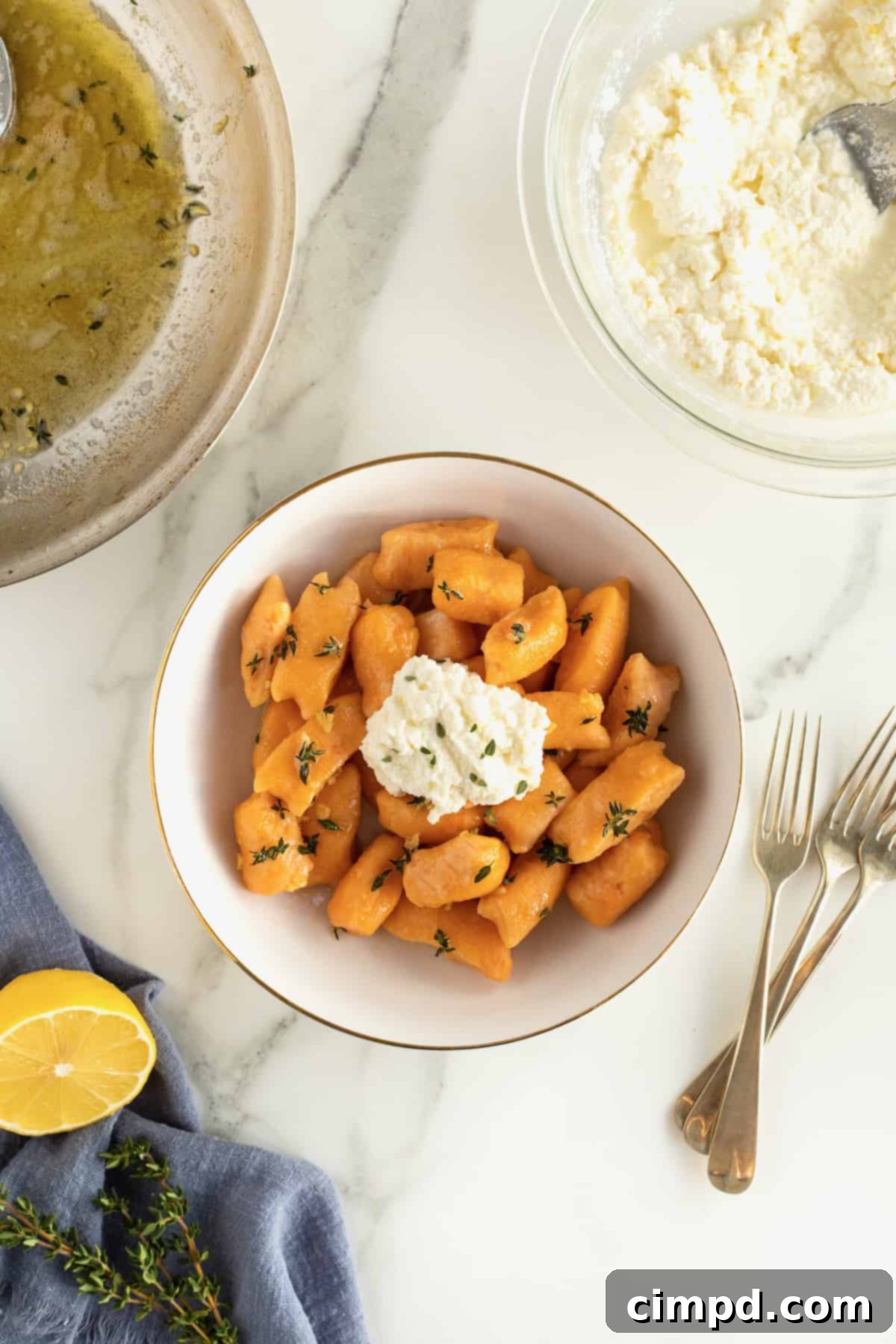 A close-up shot of a single gold-rimmed white bowl presenting a mouthwatering portion of sweet potato gnocchi with ricotta.