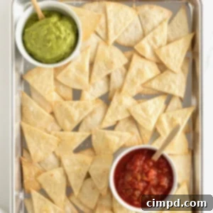 Baked triangle-cut flour on a baking sheet with a small bowl of salsa and a small bowl of guacamole.