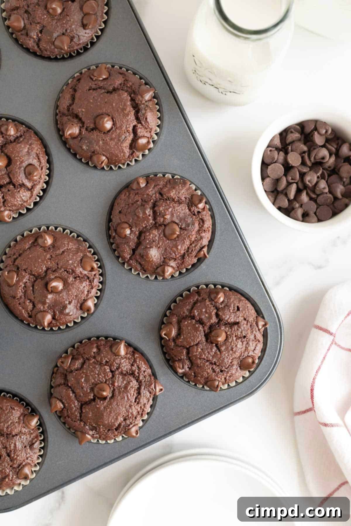 A dark aluminum muffin tin filled with perfectly baked double chocolate muffins, ready to be cooled and enjoyed.