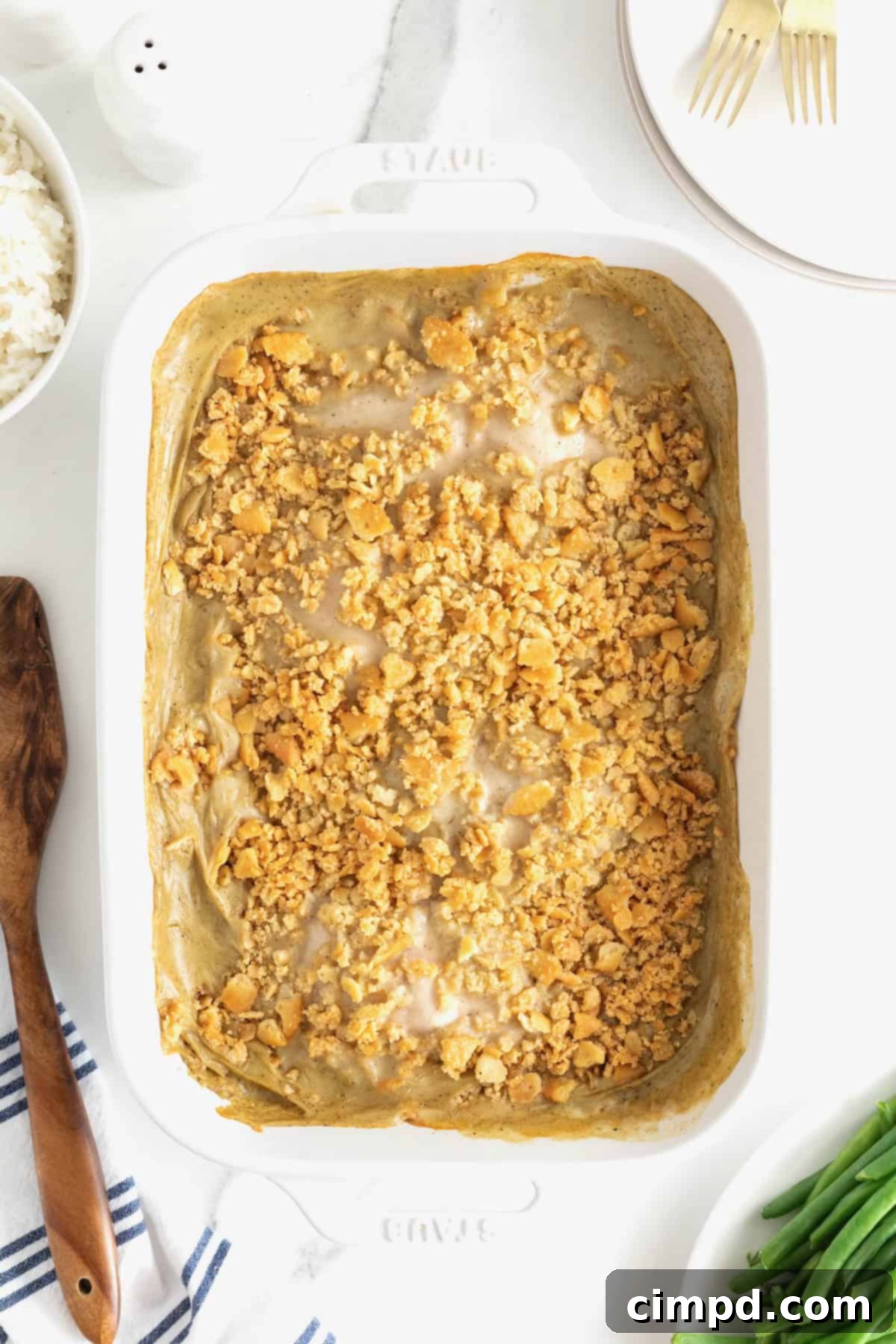 A finished white casserole dish filled with a golden-brown, bubbly creamy chicken bake, fresh out of the oven and ready to be served.
