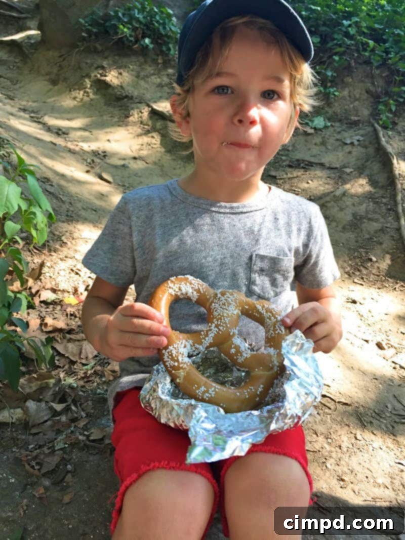 Boy happily eating a giant pretzel in Central Park