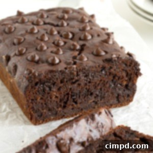 Guilt-Free Chocolate Banana Loaf 13 A loaf of healthy chocolate banana bread sliced with a knife on a floured surface.