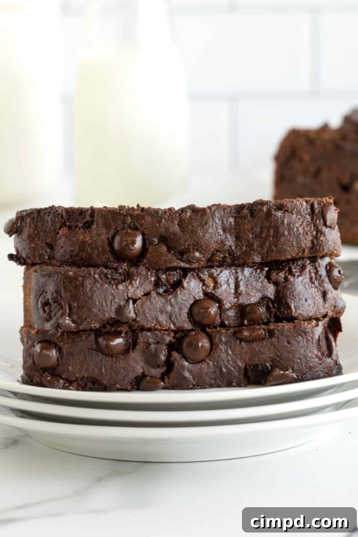 Guilt-Free Chocolate Banana Loaf 3 Three perfectly sliced pieces of healthy chocolate banana bread stacked on white ceramic plates.