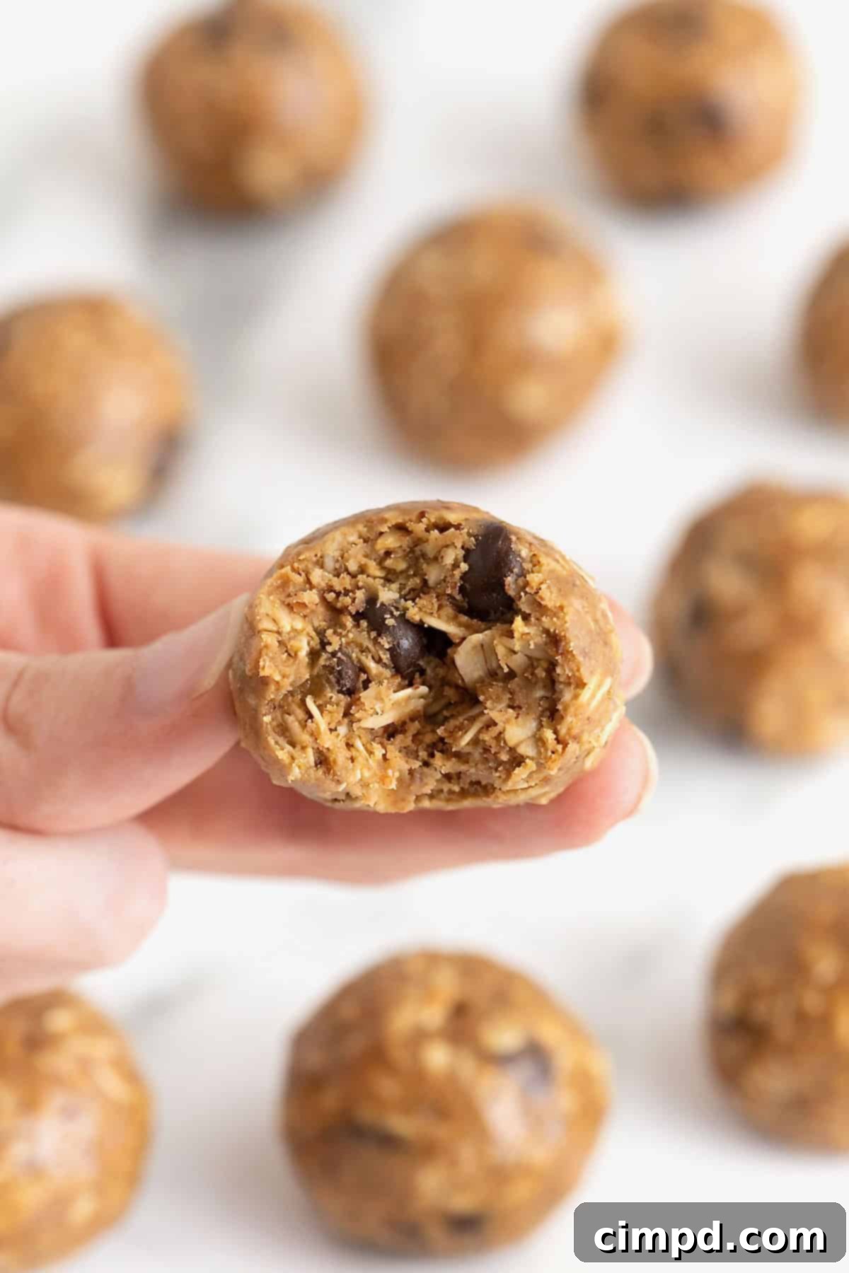 A hand holding a snack ball with a bite taken out of it.