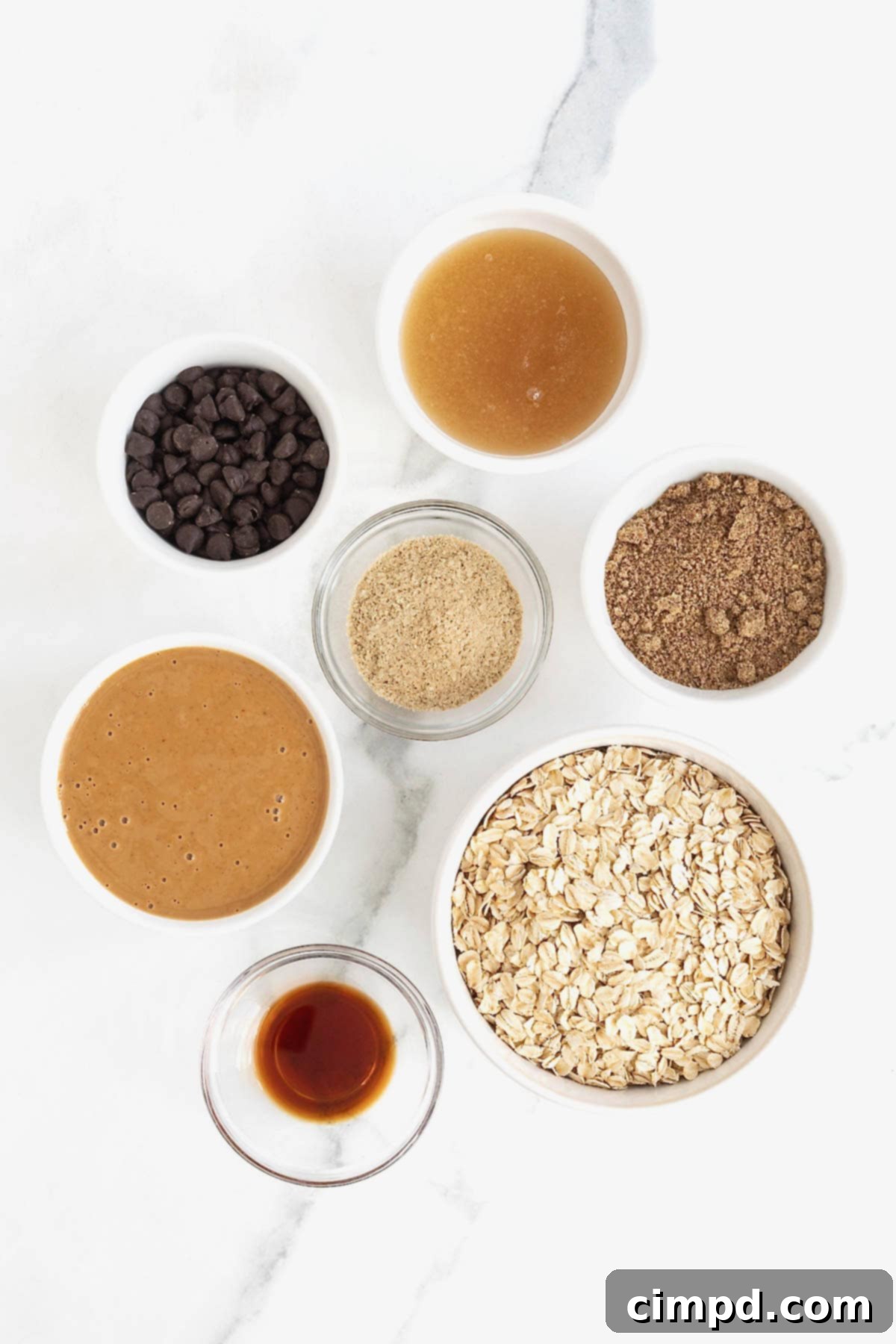 Ingredients to make lactation bites in small glass dishes on a white marble counter.