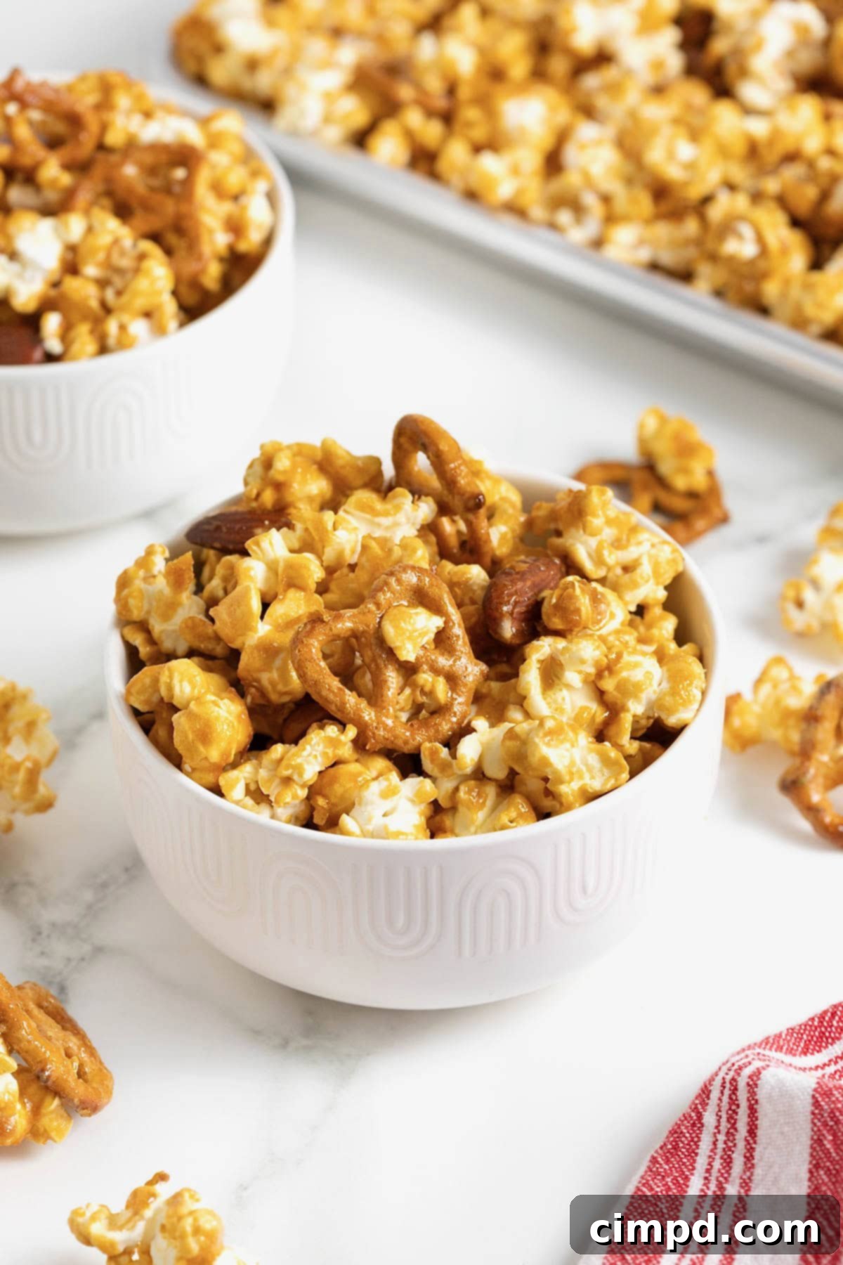 A bowl of caramel corn mix in a small white bowl on a white marble counter.