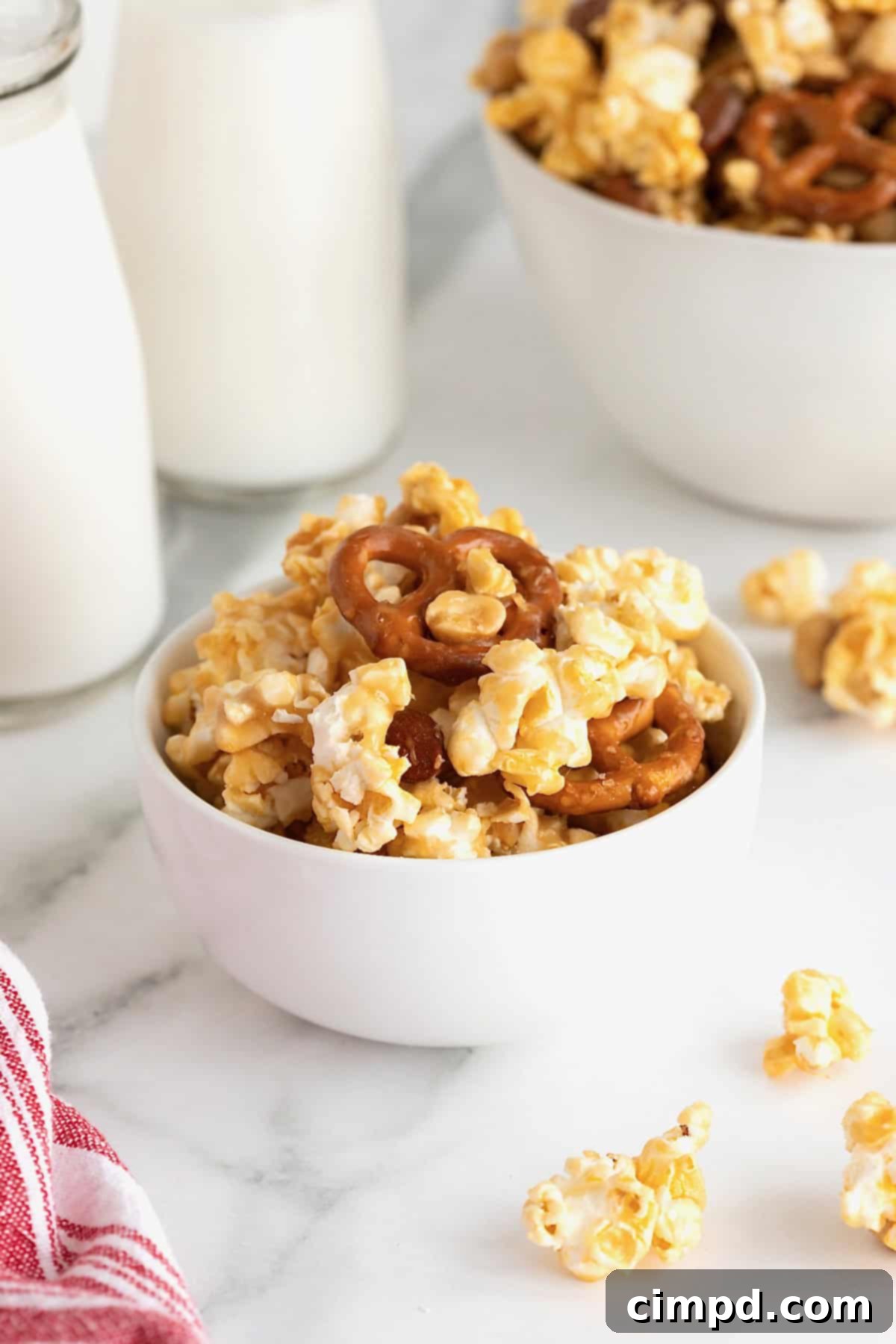 A white bowl of caramel corn mix on a white marble counter.