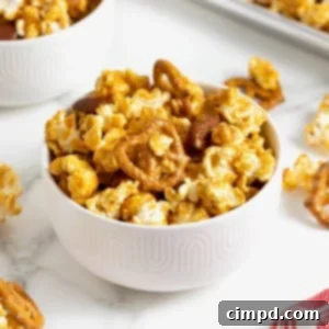 A bowl of caramel corn mixx in a small white bowl on a white marble counter.
