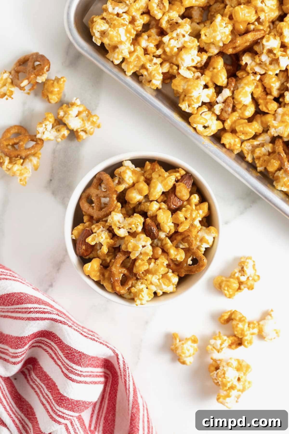A white bowl of caramel corn mix on a white marble counter.