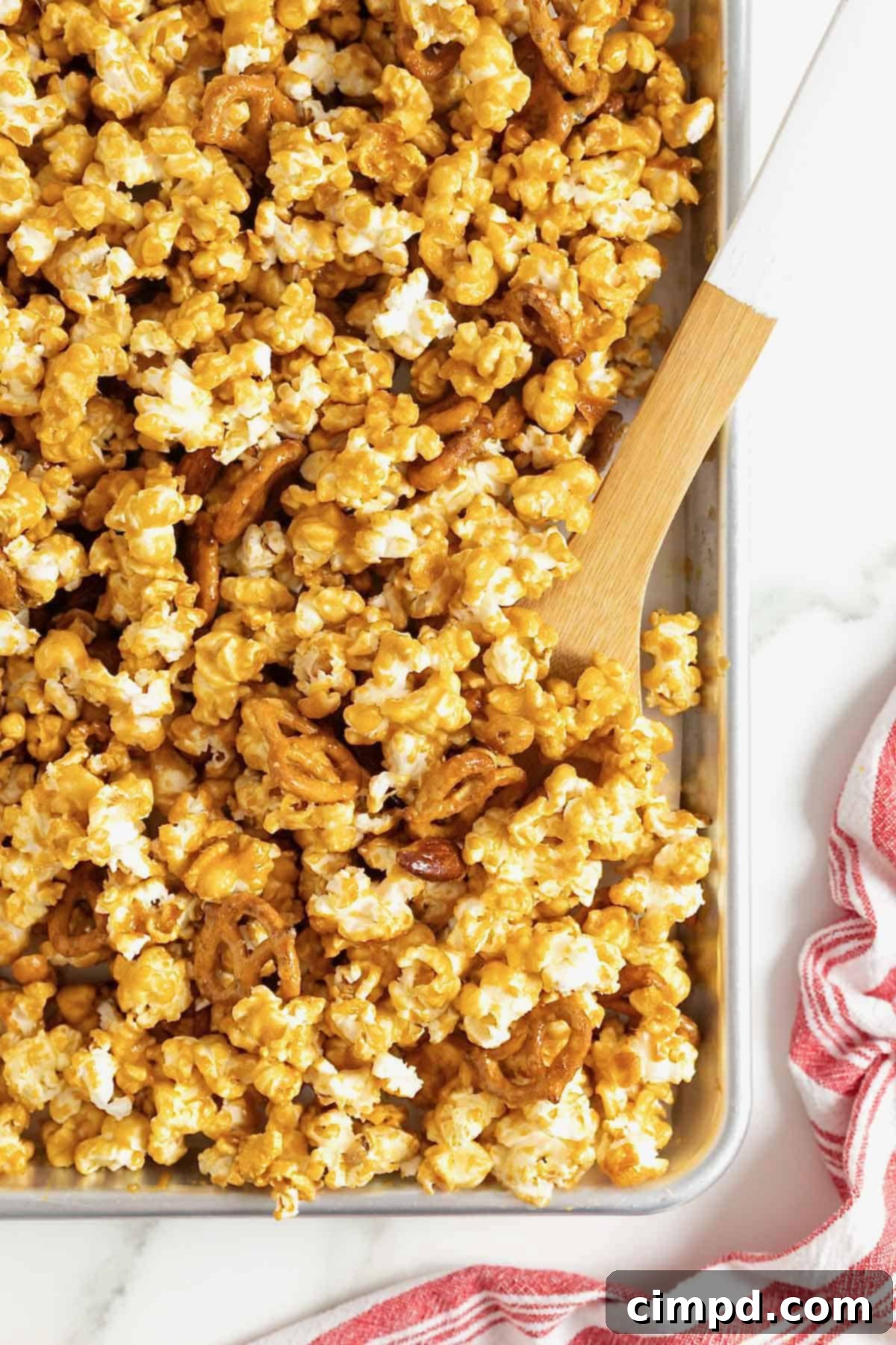 A wooden spatula in a baking sheet of baked caramel corn mix.